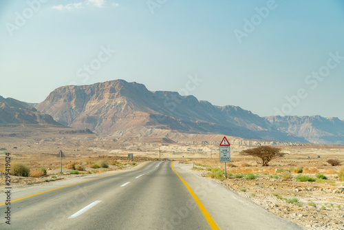 View of Two Way Highway in the Israeli Dessert With Large Mountains in the Background © porqueno