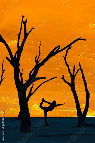 Silhouette young Asian woman practices yogaSilhouette young Asian woman practices yoga standing half moon pose at at Deadvlei, Sossusvlei , Namib desert. Landmark for tourist in NAMIBIA. Outdoor Yoga.