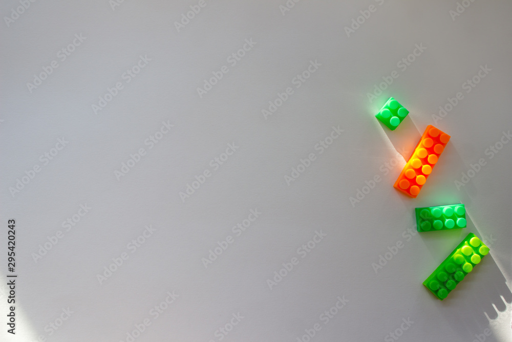 Gray background with green and orange constructor in the corner. Children`s background with constructor with empty space for text. copy space, top view, flat lay Gray background with green and orange constructor in the corner. Children`s background with constructor with empty space for text. copy space, top view, flat lay