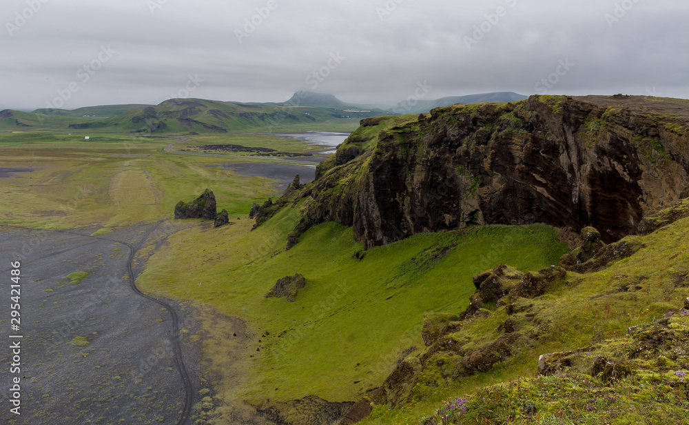 Valley scenery in green and brown colors. Top view of the valley from the mountain. Cloudy sky in the background