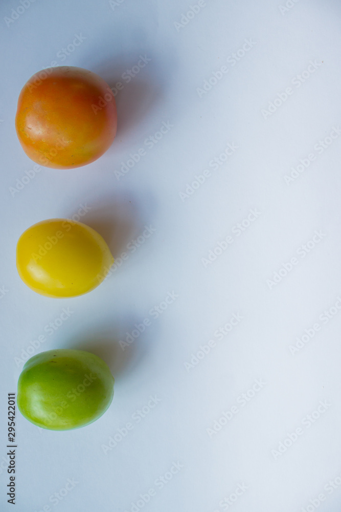 Red, yellow, green tomato on a white background. copy space, top view, flat lay, background with blank space for text Red, yellow, green tomato on a white background. copy space, top view, flat lay, background with blank space for text