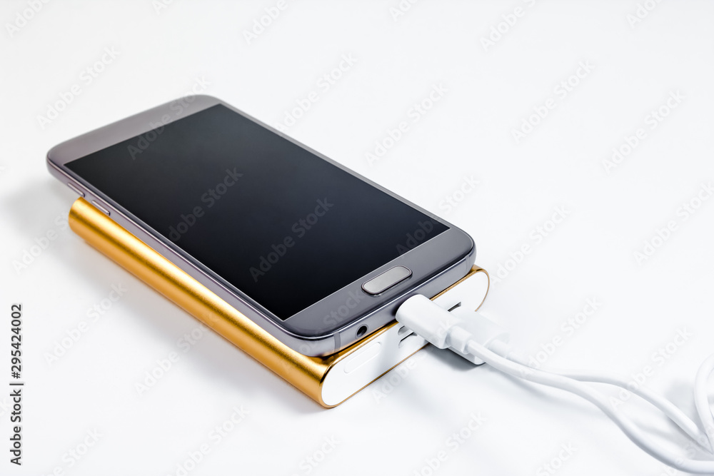 Golden powerbank with smart phone on background Golden powerbank with smart phone on background