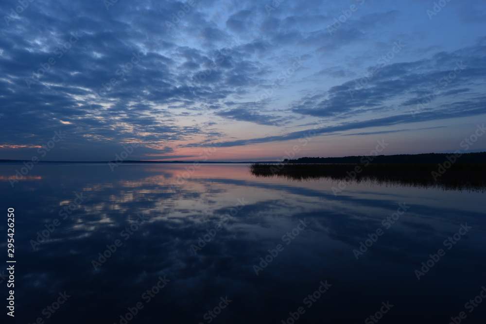Twilight blue sky in clouds reflected on lake water at sunset in the autumn evening