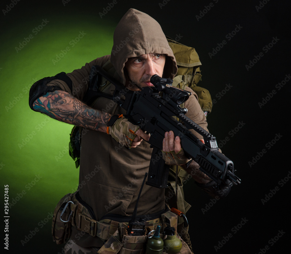 man Stalker with a gun with an optical sight and a backpack on a dark background man Stalker with a gun with an optical sight and a backpack on a dark background