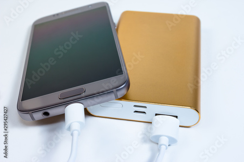 Golden powerbank with smart phone on background