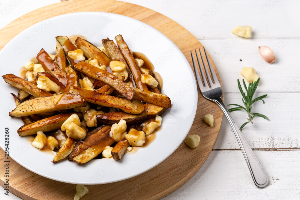 Poutine comfort food closeup. A classic fast food cuisine dish from Quebec. This canadian comfort food is made with french fries mixed with tasty cheese curds and a delicious brown gravy sauce. Poutine comfort food closeup. A classic fast food cuisine dish from Quebec. This canadian comfort food is made with french fries mixed with tasty cheese curds and a delicious brown gravy sauce.