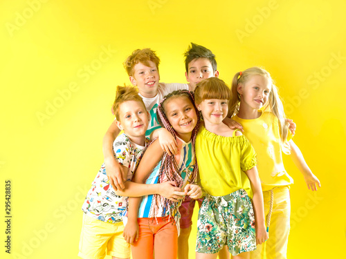 Group of happy trendy children laughing fun on a yellow background