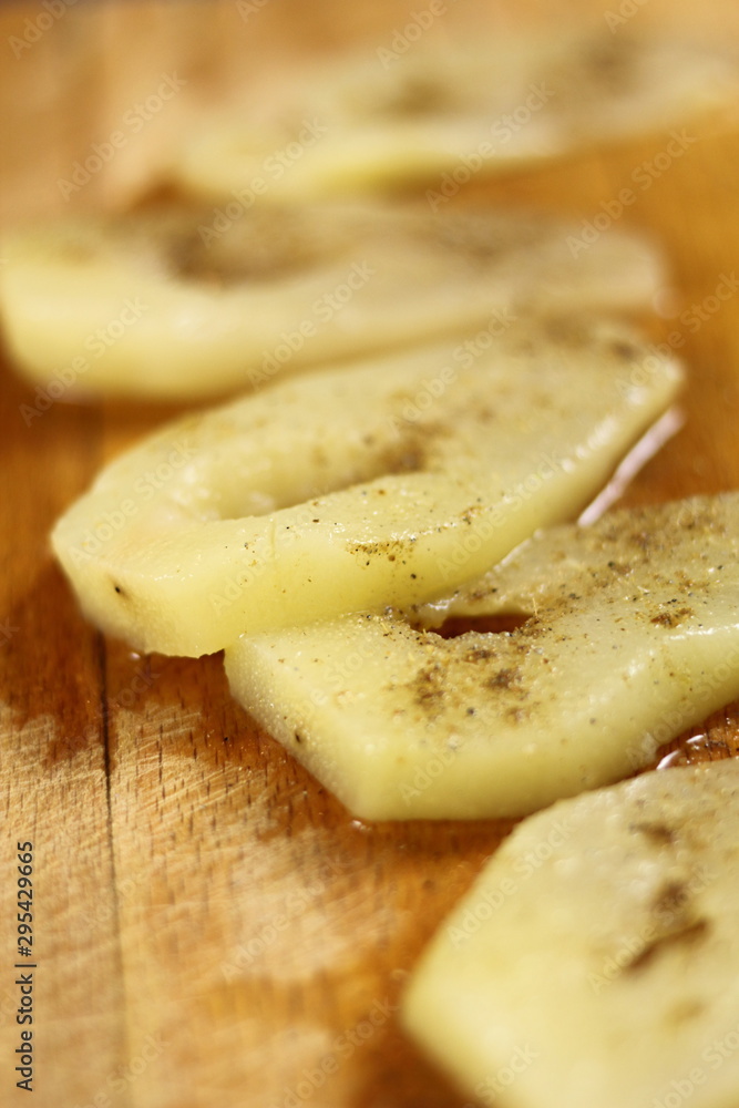 Slices of cooked pears with condiment on wooden cutting board