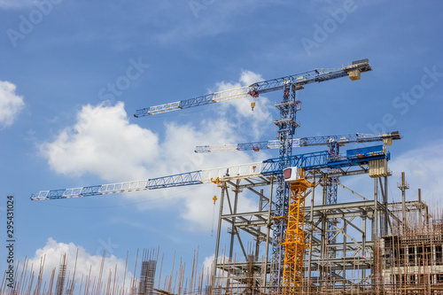 three cranes on construction site with blue sky cloud