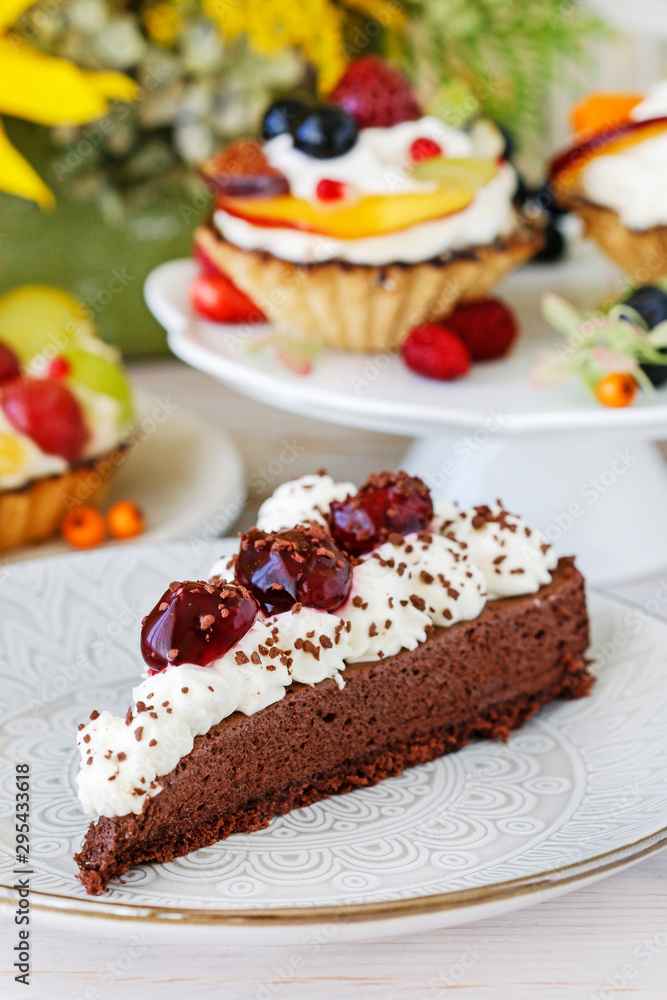 Chocolate cake with whipped cream decorated with cherries in a sweet sauce. Chocolate cake with whipped cream decorated with cherries in a sweet sauce.