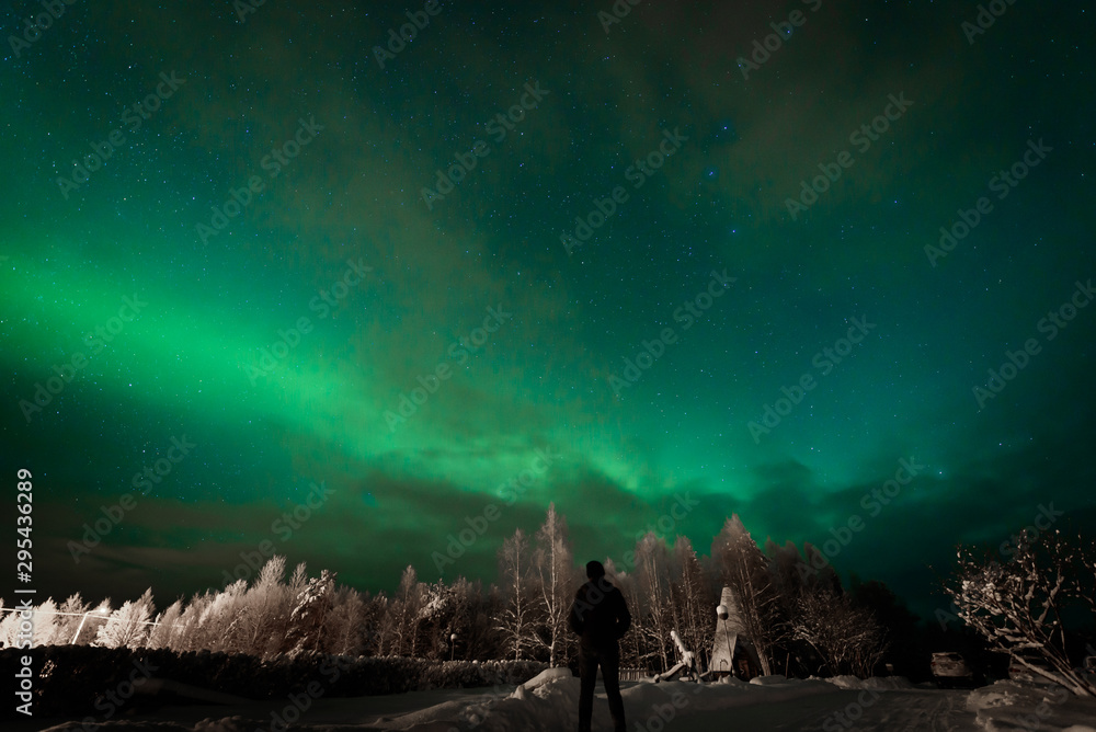 People has looking the northern lights Aurora Borealis at Kuukiuru village lake in Lapland, Finland.
