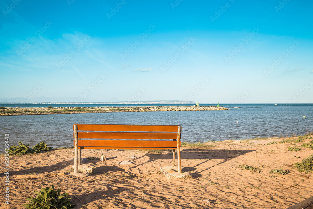 Fototapeta premium drewniana ławka do odpoczynku z widokiem na ujście rzeki Segury o zachodzie słońca. Alicante, Hiszpania