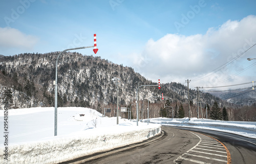 Panoramic view of driving directions With trees and mountains covered in snow