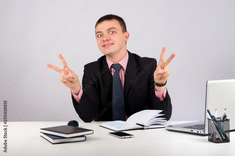Young business man showing victory sign on grey background Young business man showing victory sign on grey background