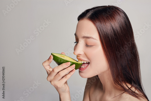 Profile side photo portrait of attractive tender brown-haired lady with perfect pure shine skin eating avocado