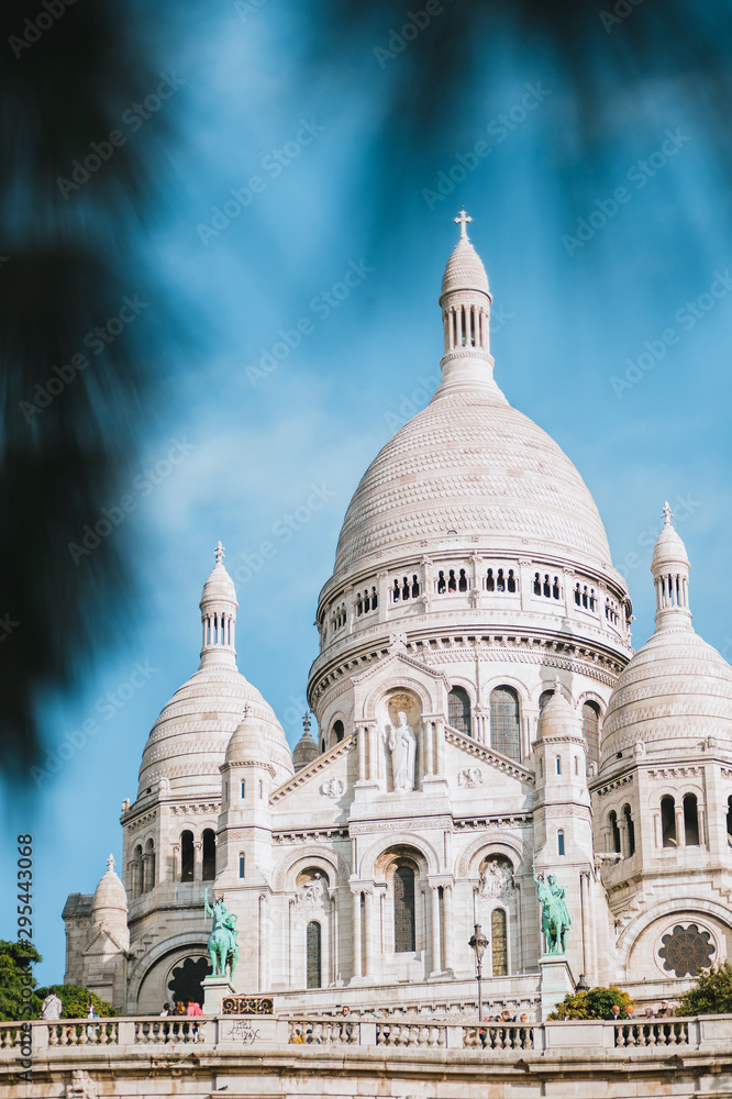White Sacre Coeur Basilica in Paris on a sunny day with blurry leaves in the foreground