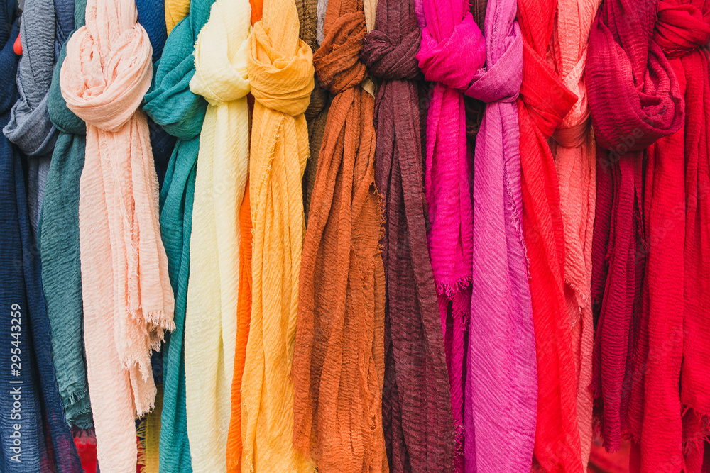 Multi-colored silk and cotton scarves on a shop hanger - bright colors in clothes