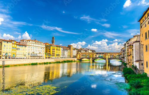 Ponte Vecchio stone bridge with colourful buildings houses over Arno River blue turquoise water and embankment promenade in historical centre of Florence city, blue sky white clouds, Tuscany, Italy © Aliaksandr