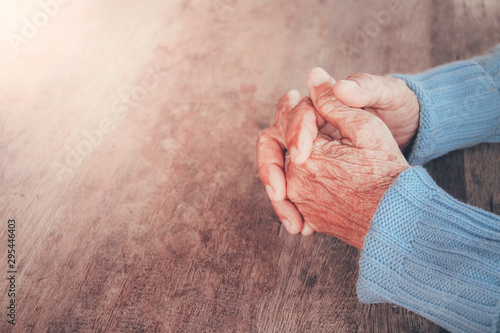 The old person's praying hand. Concept: hope, belief, dramatic loneliness, sadness, depression, cry, disappointed, healthcare, pain.