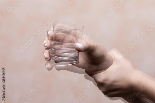 Trembling hand holding glass with alcohol drink photo