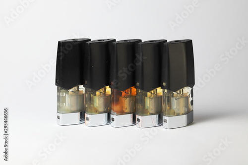 e-juice vape refill pods with liquids of different shades of orange yellow, white background isolated close up photo