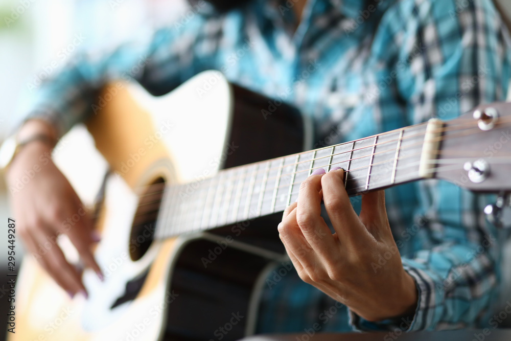 Fototapeta premium Focus on female hand playing bracket in music workshop. Professional guitar player having musical lesson for students. Art concept. Blurred background