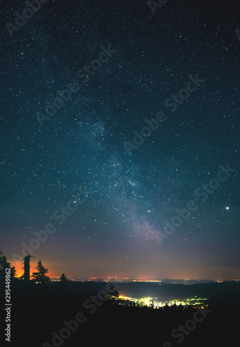 Glowing town in the mountains with the milky way galaxy and panorama mountain. view. Wurmberg  Braunlage Harz National Park  German Mountain