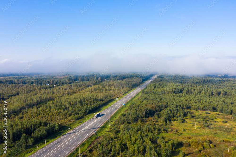 Beautiful hight way road high angle beautiful view of the fog over the road on an early summer morning in central Russia. Bird's eye view of the road and skyline.