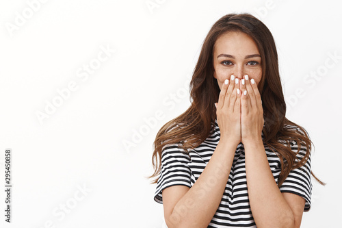 Surprised glad cute young woman in striped t-shirt ambushed with unexpected awesome b-day surprise, cover mouth gasping impressed, look camera speechless and happy, white background