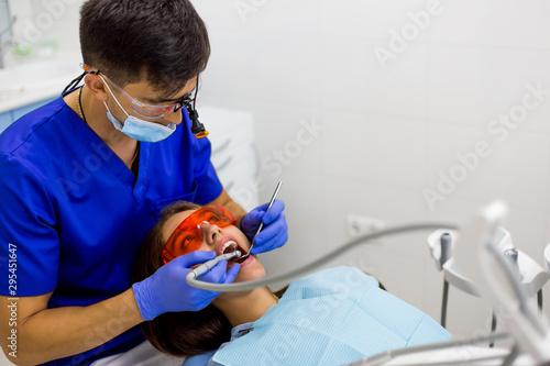 Dentist curing a female patient's caries in tooth. Dentis examines the teeth in dental clinic office.