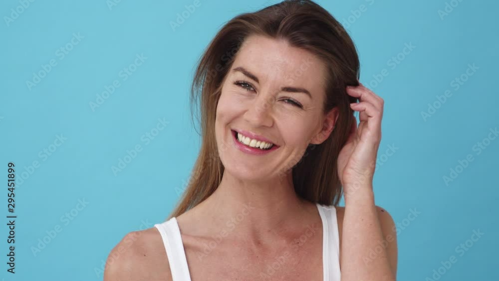 Portrait of a Woman Smiling while Fixing Her Hair Behind Her Ear Portrait of a Woman Smiling while Fixing Her Hair Behind Her Ear
