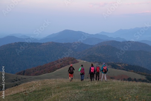 Hiking group of tourist around peak Lomis Mta in Borjomi-Kharagauli National Park, Georgia. Amazing autumn colours in evening sunlight.