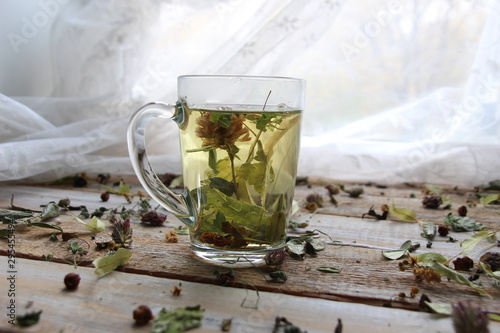 Hot herbal tea in cup on wooden background with dry herbs