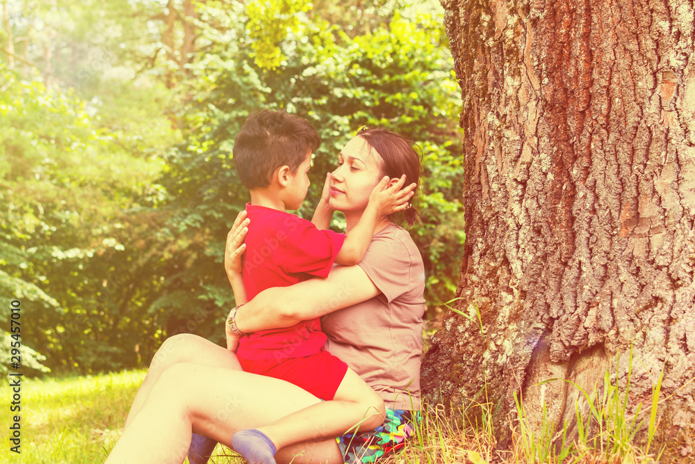 mom and son have fun under a tree in the summer. toned mom and son have fun under a tree in the summer. toned
