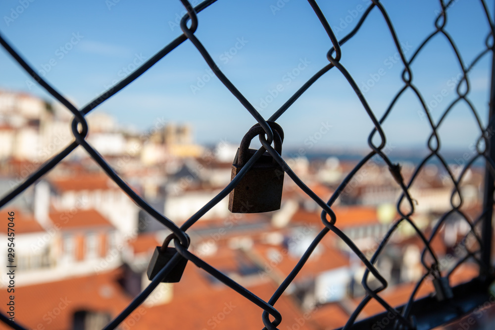 Detail of padlocks placed on the security fence of the Santa Just lift in Lisbon with the city landscape in the background Detail of padlocks placed on the security fence of the Santa Just lift in Lisbon with the city landscape in the background