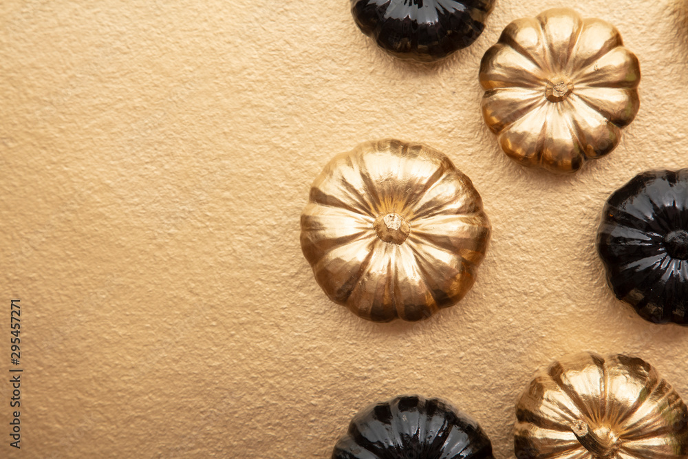 Luxury gold and black autumn pumpkin flat lay composition on a gold background Luxury gold and black autumn pumpkin flat lay composition on a gold background