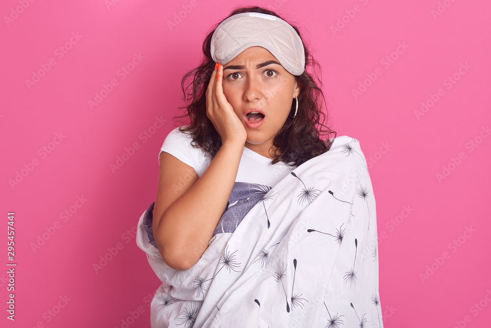 Close up portrait of sleepy young woman with sleeping mask on head and wearing blanket isolated over rose studio background, adorable female with shocked facial expression, hears shocking news. Close up portrait of sleepy young woman with sleeping mask on head and wearing blanket isolated over rose studio background, adorable female with shocked facial expression, hears shocking news.