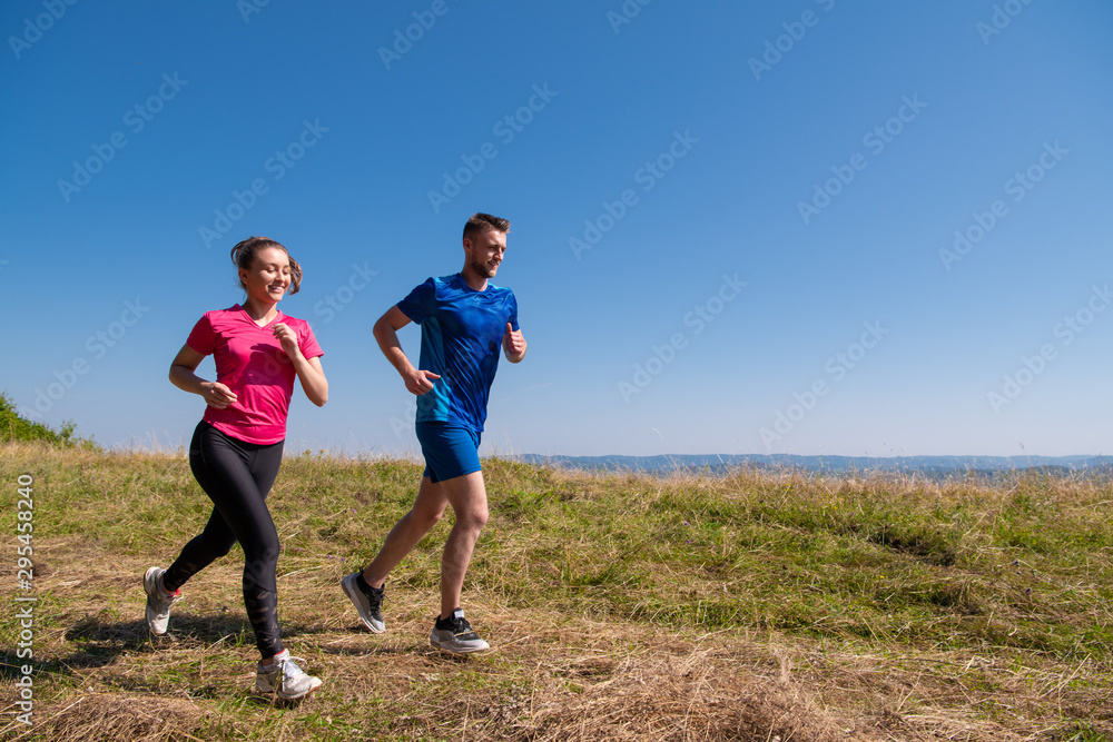young couple jogging on sunny day at summer mountain young couple jogging on sunny day at summer mountain
