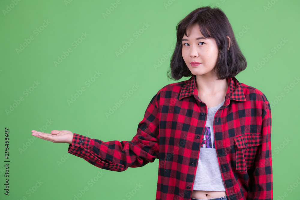 Portrait of beautiful Asian hipster woman showing something Portrait of beautiful Asian hipster woman showing something