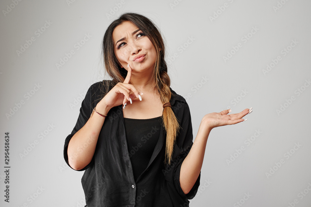 Attractive Kazakh Asian young pensive woman in total black thought and pretends to hold your product or text in palm isolated on white Attractive Kazakh Asian young pensive woman in total black thought and pretends to hold your product or text in palm isolated on white