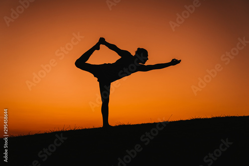 Wallpaper Mural silhouette of young man in a park doing yoga sport. orange sky background. healthy lifestyle. Torontodigital.ca