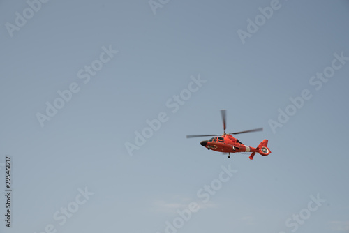 Orange helicopter flying in a cloudless sky