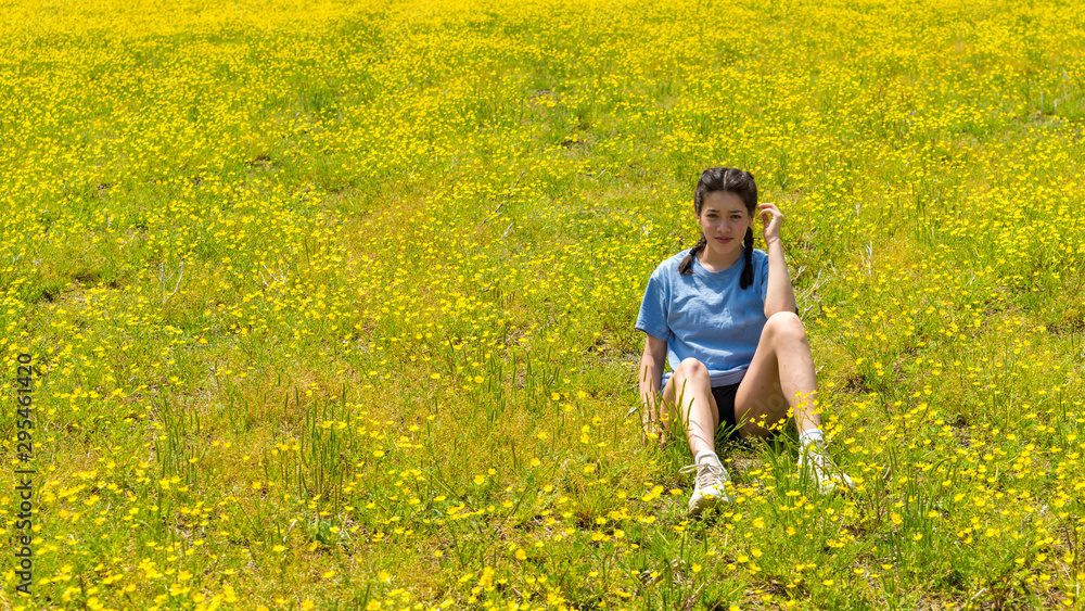 Teen girl with braids sitting in large field with yellow flowers Teen girl with braids sitting in large field with yellow flowers