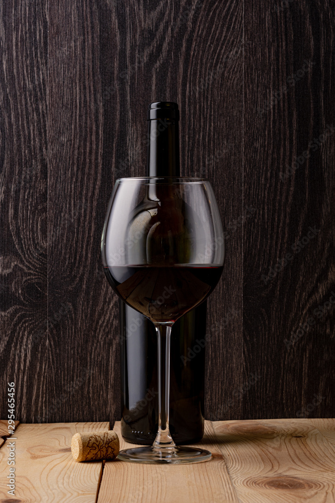 Wine bottle and a glass of wine. Wood background. Natural cork.