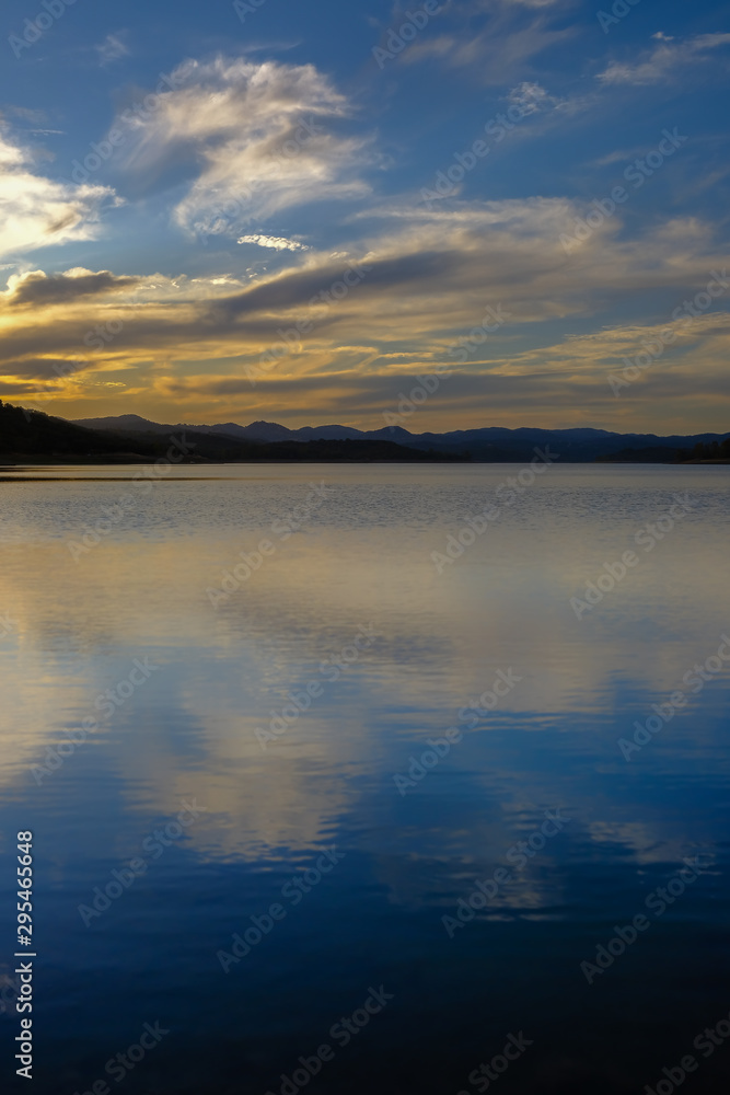Vertical view of a sunset in a lake under a cloudy sky