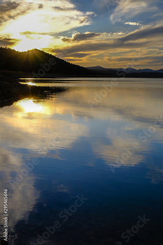 Vertical view of a sunset in a lake under a cloudy sky