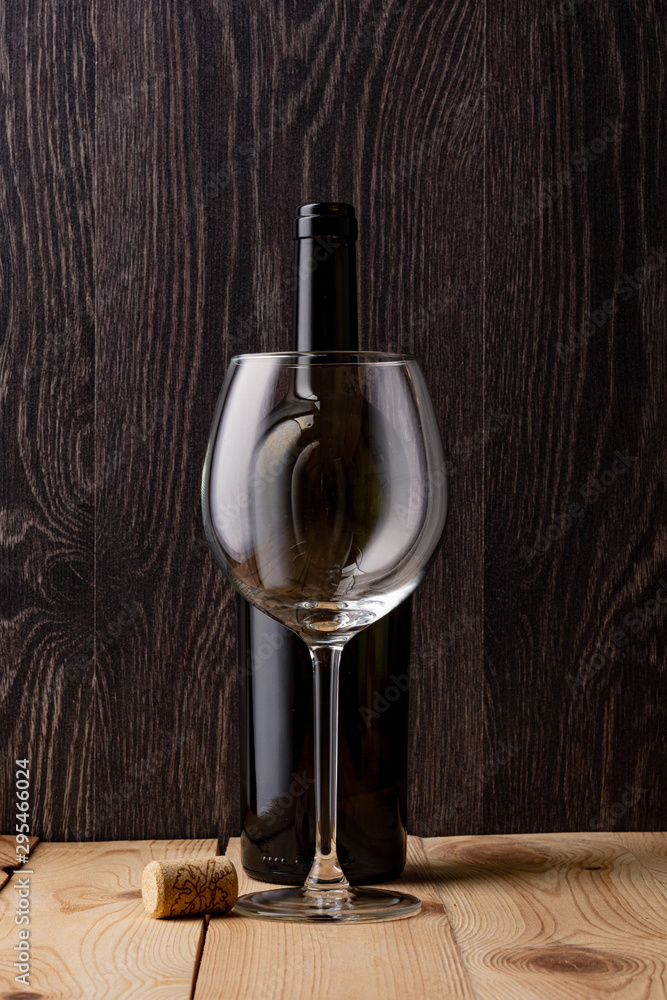 Wine bottle and a glass of wine. Wood background. Natural cork.