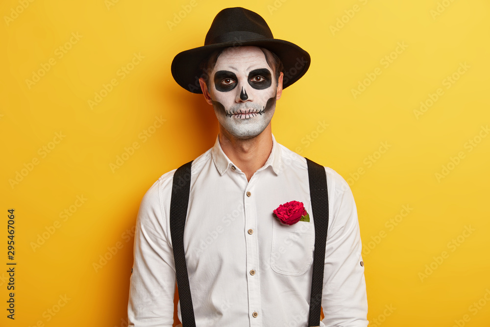 Portrait of serious male zombie wears skull mask, horrible makeup ...