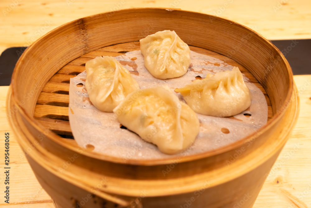 White meat, shrimps and mushroom steamed dumplings on a wooden table in a wooden steamer in an asian restaurant or chinese bar with dumplings. White meat, shrimps and mushroom steamed dumplings on a wooden table in a wooden steamer in an asian restaurant or chinese bar with dumplings.