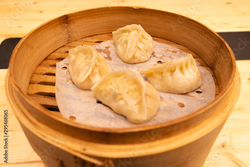 White meat, shrimps and mushroom steamed dumplings on a wooden table in a wooden steamer in an asian restaurant or chinese bar with dumplings.